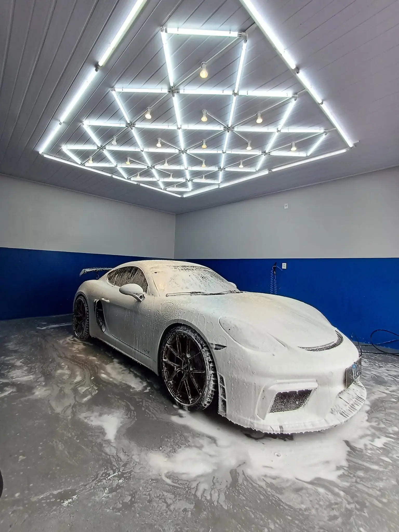 Porsche coberto de espuma sob o teto de luzes geométricas do estúdio Peppa