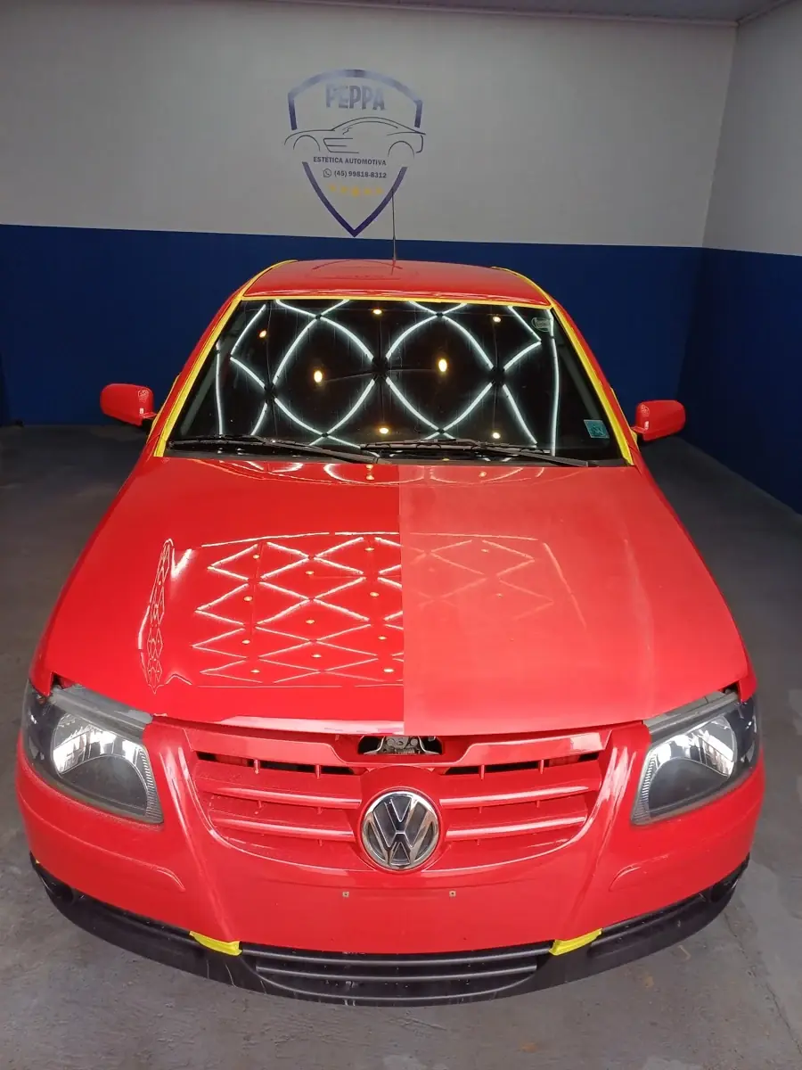 Volkswagen vermelho com o reflexo das luzes geométricas sobre o capô
